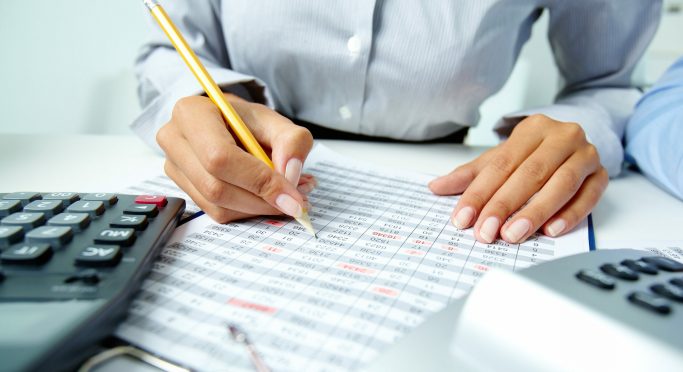 Photo of human hands holding pencil and ticking data in documents