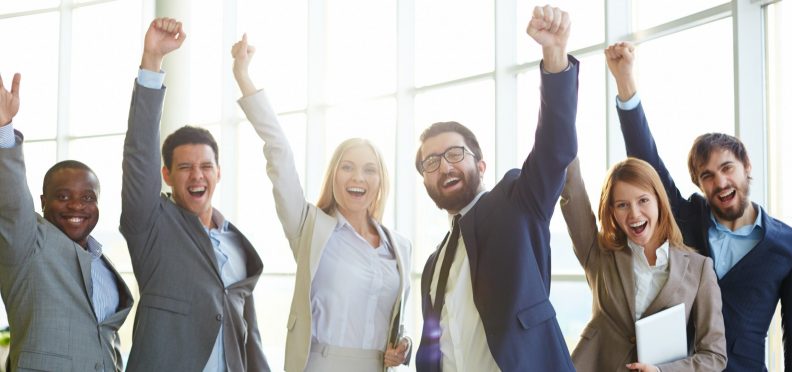Group of ecstatic business partners looking at camera with raised arms